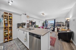 Kitchen island with integrated double basin sink, stainless steel dishwasher, white cabinetry, and a light-toned countertop - 