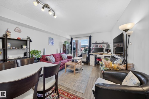 Open-concept living area featuring wood-finish flooring, recessed lighting, and a sliding glass door to an exterior space - #419 920 156 St Nw, Edmonton, AB 