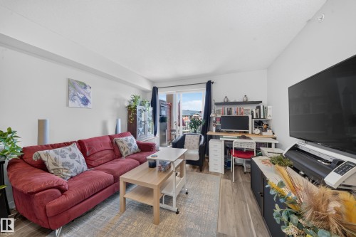 Wood-finish flooring throughout, white painted walls, and a sliding glass door to an exterior space - #419 920 156 St Nw, Edmonton, AB 
