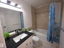 Bathroom featuring a vanity with a dark countertop, an undermount sink, and a large mirror - 140 Dickinsfield Court Nw, Edmonton, AB 