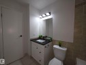 White vanity with a black countertop, rectangular undermount sink, and matte black faucet - 140 Dickinsfield Court Nw, Edmonton, AB 