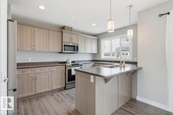 Kitchen featuring wood-finish cabinetry, stainless steel appliances, a double basin sink, recessed lighting, and pendant lights - 