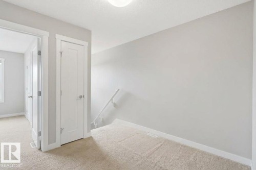 Light-colored carpeted flooring, white trim, and a white interior door with a silver-tone handle - #12 1391 Starling Dr Nw, Edmonton, AB 