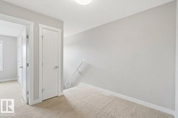 Light-colored carpeted flooring, white trim, and a white interior door with a silver-tone handle - 