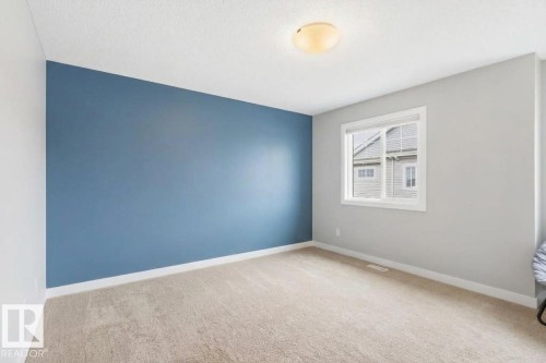 Neutral carpeting, white trim, single window, flush mount ceiling light, and a blue accent wall - #12 1391 Starling Dr Nw, Edmonton, AB 