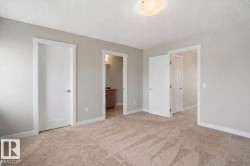 Neutral tone wall paint, textured ceiling, flush mount ceiling light fixture, carpeted flooring, white trim and doors - 