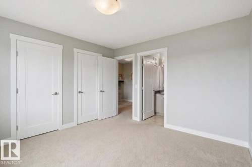 Neutral-toned carpeting, light gray wall paint, multiple white paneled doors, and a flush mount ceiling light - #12 1391 Starling Dr Nw, Edmonton, AB 