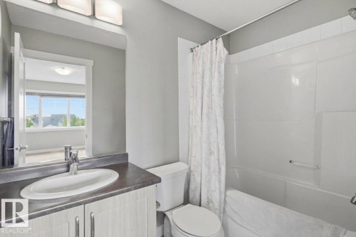 White bathroom vanity with an integrated sink and chrome faucet, set against a grey wall - #12 1391 Starling Dr Nw, Edmonton, AB 