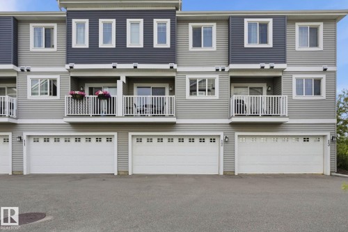 Multi-level townhome exterior featuring light gray horizontal siding and dark gray vertical siding - #12 1391 Starling Dr Nw, Edmonton, AB 