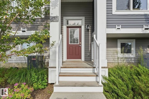 Entry with a paneled door and transom window, flanked by outdoor lighting - #12 1391 Starling Dr Nw, Edmonton, AB 