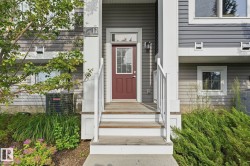 Entry with a paneled door and transom window, flanked by outdoor lighting - 