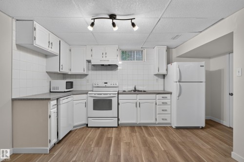 Wood-finish flooring, white cabinetry, track lighting, white appliances, and tiled backsplash - 2 Grandora Crescent, St. Albert, AB 