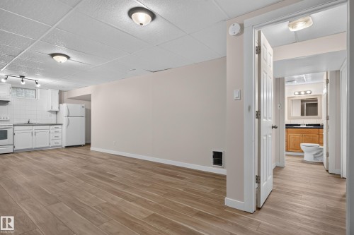 Wood-finish flooring, white kitchen cabinetry, white tile backsplash, and a bathroom with a wood-finish vanity - 2 Grandora Crescent, St. Albert, AB 