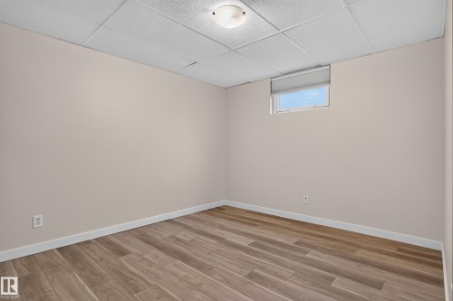 Wood-finish plank flooring, neutral wall tones, drop ceiling, and a window with roller shade - 2 Grandora Crescent, St. Albert, AB 