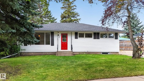 White siding exterior with a dark shingle roof, complemented by a vibrant red entry door - 2 Grandora Crescent, St. Albert, AB 