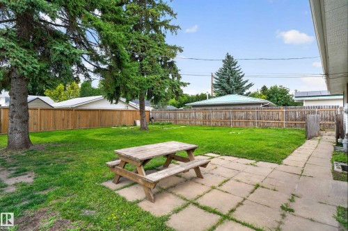 Expansive backyard featuring a manicured lawn, mature trees, wood fence, and a stone paver pathway - 2 Grandora Crescent, St. Albert, AB 