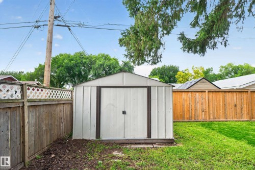 Detached storage shed with double doors, wood fencing with lattice detailing, and a manicured lawn area - 2 Grandora Crescent, St. Albert, AB 