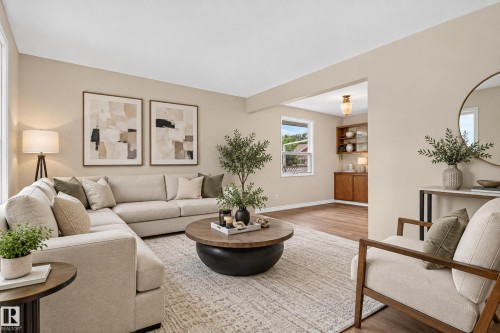 Expansive living area with light-toned walls, wood-finish flooring, and a built-in wooden cabinet with glass-front shelving - 2 Grandora Crescent, St. Albert, AB 