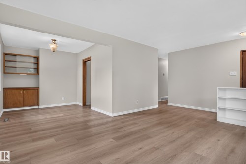 Wood-finish flooring, light gray wall paint, built-in wooden cabinetry with glass-front display, and a white built-in shelving unit - 2 Grandora Crescent, St. Albert, AB 