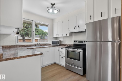 White cabinetry, stainless steel appliances, wood-finish flooring, L-shaped countertop, and tile backsplash - 2 Grandora Crescent, St. Albert, AB 