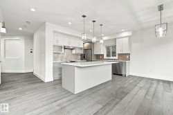 Kitchen featuring a center island, white cabinetry, integrated stainless steel appliances, mosaic tile backsplash, and wood-finish flooring - 