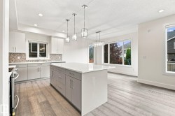 Kitchen featuring a central island with white countertop, recessed lighting, pendant light fixtures, wood-finish flooring, and ample natural light from multiple windows - 
