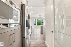 Stainless steel microwave and refrigerator, light-toned cabinetry, and wood-finish flooring - 