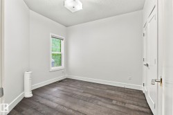 Hardwood-style flooring, white trim, and a window with a roller shade - 