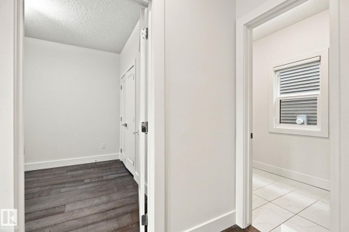 Hallway featuring wood-finish flooring and white interior doors - 4530 Saly Place Sw, Edmonton, AB 
