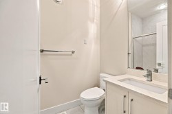 Modern vanity with integrated sink, polished chrome fixtures, frameless mirror, and a glass-enclosed shower with tiled walls - 