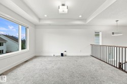Tray ceiling with recessed lighting and a central light fixture, featuring gray carpeting, white walls, and a large window - 