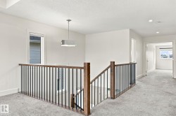 Staircase featuring wood-finish handrails and black metal balusters, recessed lighting, and a contemporary pendant light fixture - 