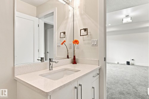 Modern vanity with a light-toned countertop, integrated sink, and chrome-finish faucet - 4530 Saly Place Sw, Edmonton, AB 
