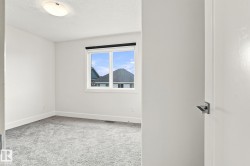 Light gray textured carpeting, white painted walls, natural light from a window, flush-mount ceiling light fixture, and a white interior door with a lever handle - 
