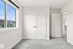 Light gray carpet flooring, white walls, white trim, white doors with dark hardware, and a large window - 