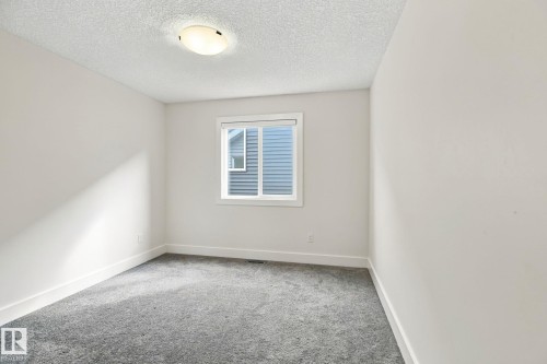 White walls with grey carpet flooring, a single window, and a flush-mount ceiling light - 4530 Saly Place Sw, Edmonton, AB 