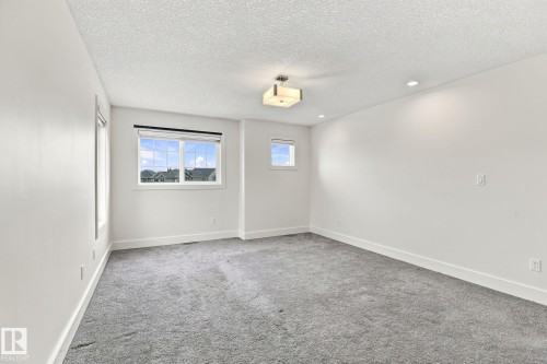 Bright interior with light gray carpeting, a window, a smaller window, and recessed lighting - 4530 Saly Place Sw, Edmonton, AB 