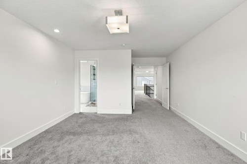 Spacious room with gray carpeting, white walls, recessed lighting, and a contemporary ceiling fixture - 4530 Saly Place Sw, Edmonton, AB 