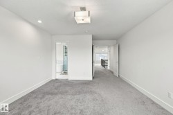 Spacious room with gray carpeting, white walls, recessed lighting, and a contemporary ceiling fixture - 