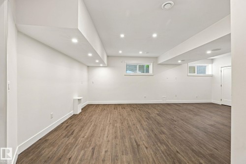 Spacious room featuring wood-finish flooring, recessed lighting, white walls, and built-in shelving - 4530 Saly Place Sw, Edmonton, AB 