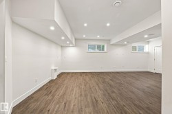 Spacious room featuring wood-finish flooring, recessed lighting, white walls, and built-in shelving - 