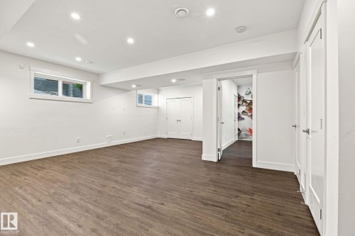 Spacious room featuring wood-finish flooring, recessed lighting, and multiple windows - 4530 Saly Place Sw, Edmonton, AB 