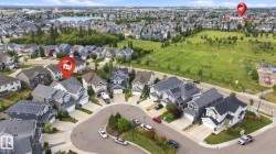 Residential neighborhood with a curved street layout, individual homes, a body of water, and surrounding green spaces - 