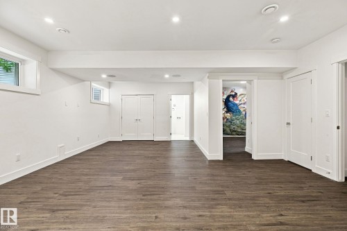 Spacious room featuring wood-finish flooring, recessed lighting, white trim, and multiple windows - 4530 Saly Place Sw, Edmonton, AB 