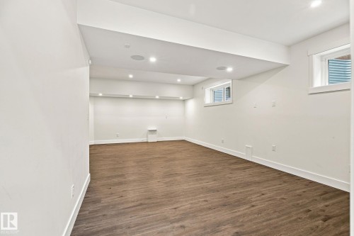 Expansive room featuring wood-finish flooring, recessed lighting, and multiple windows - 4530 Saly Place Sw, Edmonton, AB 