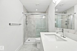 Glass-enclosed shower with tile surround, a built-in vanity with an integrated sink, and a large wall-mounted mirror - 
