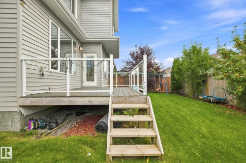 Deck with glass panel railing and steps to a grassy yard - 4530 Saly Place Sw, Edmonton, AB 