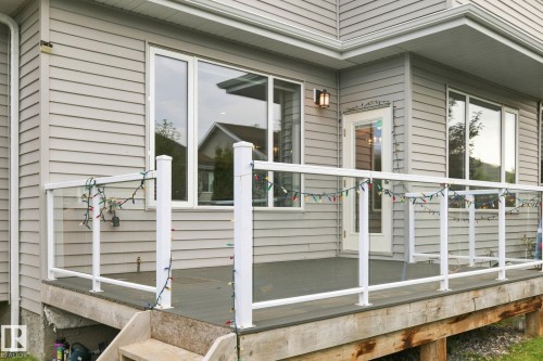Expansive deck featuring a glass railing system, multiple windows, and exterior wall lantern - 4530 Saly Place Sw, Edmonton, AB 