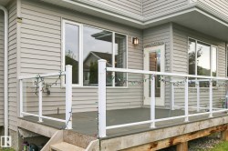 Expansive deck featuring a glass railing system, multiple windows, and exterior wall lantern - 