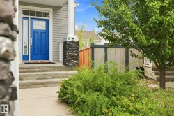 Siding exterior with a vibrant blue entry door, concrete steps, and a stone-clad column - 